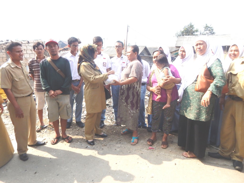 Kepala SMAN 1 Depok menyerahkan bantuan kepada salah satu korban kebakaran di kampung Lio, Panmas-Depok